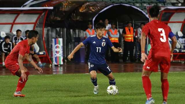 Dua pemain Timnas Myanmar saat mengadang pergerakan pemain Timnas Jepang, Takefusa Kubo, dalam matchday kedua Grup F kualifikasi Piala Dunia 2022 di Stadion Thuwunna, Yangon (10/9/2019). (AFP/Sai Aung Main)