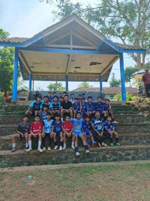 Kiper Persib Bandung, Fitrul Dwi Rustafa (Baju Hitam) berfoto bersama anak didik nya di SSB Gemar Football sebelum berlatih di Lapangan Giri Raga, Desa Margalaksana, Kecamatan Bungbulang, Kabupaten Garut, Senin (10/6/2024). SSB Gemar Football merupakan SSB milik sang ayah Maman Rado yang merupakan mantan pemain Persigar Garut. (Bola.com/Nandang Permana)