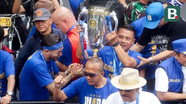 Pemain Persib Bandung, Dedi Kusnandar, mengangkat trofi saat pawai juara di Bandung, Minggu (25/5/2025). (Bola.com/M Iqbal Ichsan)