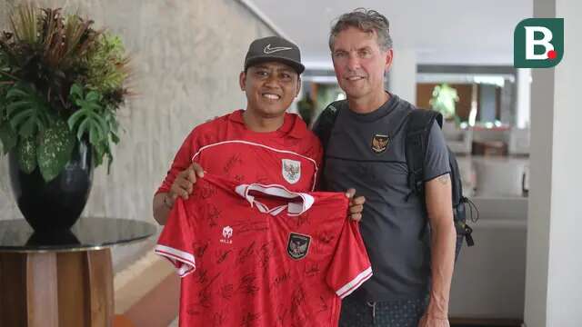 Satu di antara suporter fanatik Timnas Indonesia, Heri Istiawan, saat berfoto dengan asisten pelatih Alex Pastoor. Pria asal Banyuwangi itu sampai merogoh kocek balasan juta untuk menginap di hotel yang sama dengan Tim Garuda. (Bola.com/Alit Binawan)