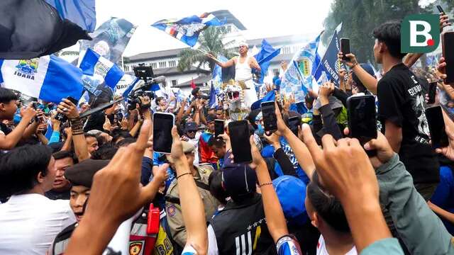 Gubernur Jawa Barat, Dedi Mulyadi, mengibarkan bendera saat merayakan Persib Bandung juara BRI Liga 1 di Gedung Sate, Bandung, Jawa Barat, Minggu, (25/5/2025). (Bola.com/M Iqbal Ichsan)