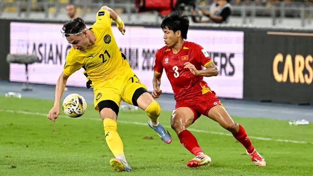 Pemain Malaysia, Dion Cools (kiri) berebut bola dengan pemain Vietnam, Nguyen Van Vi dalam laga Grup F Kualifikasi Piala Asia 2027 di Stadion Nasional Bukit Jalil, Kuala Lumpur, Malaysia, Selasa (10/06/2025). (AP Photo/Vincent Thian)