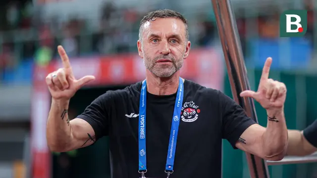 Pelatih Persija Jakarta, Thomas Doll, menunjukkan lambang khas The Jak sebelum pertandingan pekan ke-23 BRI Liga 1 2023/2024 antara Persija Jakarta melawan PSS Sleman yang berlangsung di Stadion Patriot Chandra Bhaga, Bekasi, Sabtu (16/12/2023). (Bola.com/Bagaskara Lazuardi)