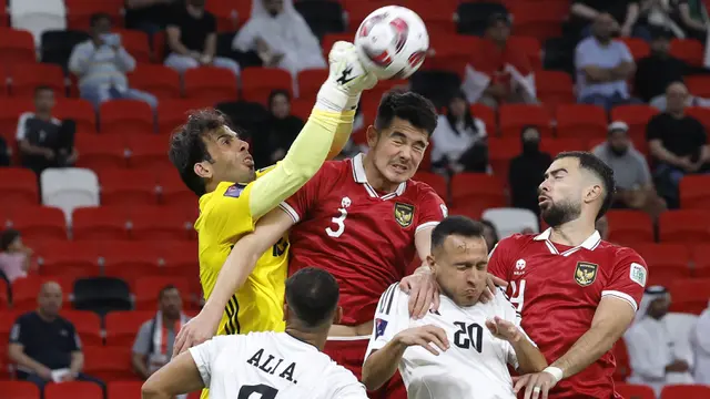 Kiper Timnas Irak, Jalal Hassan (kiri), berusaha menghalau bola dari ancaman bek Timnas Indonesia, Elkan Baggott (tengah), pada laga pertama Grup D Piala Asia 2023 Qatar di Ahmad bin Ali Stadium, Al-Rayyan, Doha, Senin (15/1/2024). (AFP/Karim Jaafar)