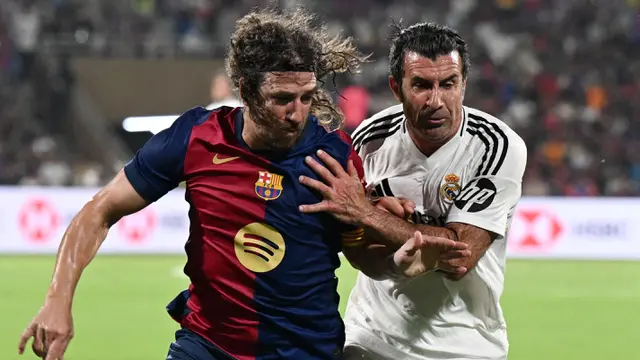 Legenda Barcelona, Carles Puyol (kiri) berebut bola dengan legenda Real Madrid, Luis Figo dalam laga persahabatan yang berlangsung di DY Patil Stadium, Navi Mumbai, India. (AFP/Punit Paranjpe)
