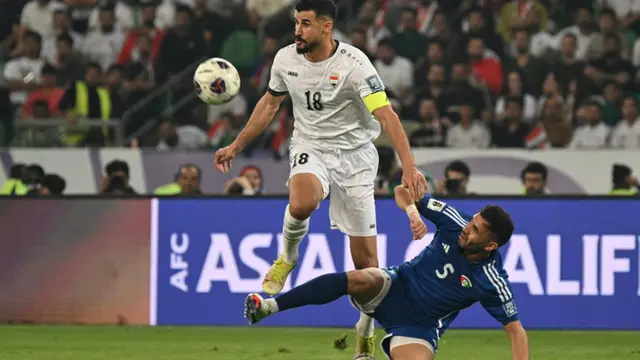 Gelandang Irak #18, Aymen Hussein, berebut bola dengan bek Kuwait #5, Fahad Al-Hajeri, dalam pertandingan kualifikasi Piala Dunia FIFA 2026 zona Asia Grup B antara Irak dan Kuwait di Stadion Internasional Basra pada 20 Maret 2025. (Hussein FALEH/AFP)