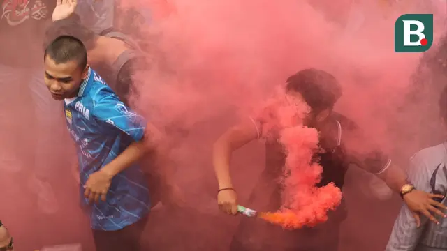 Seorang fans menyalakan suar saat melakukan pawai di Kota Bandung, Sabtu (1/6/2024) untuk menyambut kedatangan skuad Persib Bandung usai menjadi juara Championship Series BRI Liga 1 2023/2024. (Bola.com/M Iqbal Ichsan)