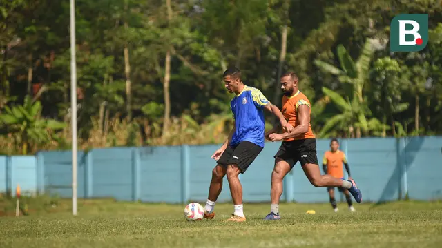 Yann Motta (rompi biru) dibayangi Dalberto Luan dalam sesi latihan Arema FC di lapangan ARG, Kabupaten Malang, Rabu (02/07/2025). (Iwan Setiawan/Bola.com)