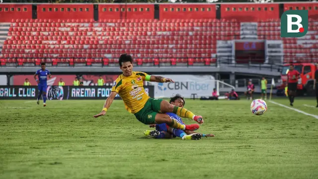 Pemain Persebaya Surabaya Bruno Moreira mendapatkan tekelan dari pemain Arema FC Ahmad Maulana di Stadion Kapten I Wayan Dipta. (Alit Binawan/Bola.com)
