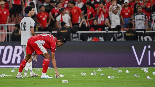 Pemain Timnas Indonesia, Rizky Ridho, memunguti gelas air yang dilempar suporter saat pertandingan babak keempat Grup B Kualifikasi Piala Dunia 2026 zona Asia antara Irak dan Indonesia di Stadion Alinma Bank, King Abdullah Sports City, Jeddah, Arab Saudi, Minggu (12-10-2025) dini hari WIB. (Foto AP/Ali Issa)