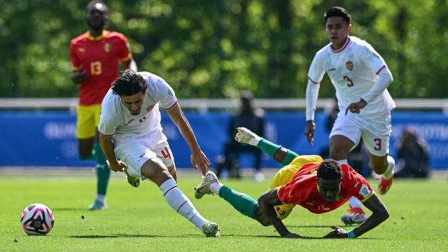 Bek Guinea U-23, Saidou Sow (kanan) terjatuh usai perebutan bola dengan bek Timnas Indonesia U-23. Nathan Tjoe-A-On pada laga play-off antar-konfederasi menuju Olimpiade Paris 2024 di Stade Pierre Pibarot, Centre National du Football de Clairefontaine, Prancis, Kamis (9/5/2024). (AFP/Miguel Medina)