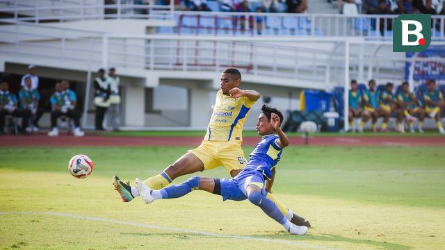 Bek kiri Arema FC, Johan Alfarizi menjuauhkan bola dari kejaran striker Persib Bandung, Uilliam Barros dalam laga pekan keenam BRI Super League 2025/2026 di Stadion Kanjuruhan, Kabupaten Malang, Senin (22/9/2025). (Bola.com/Iwan Setiawan).
